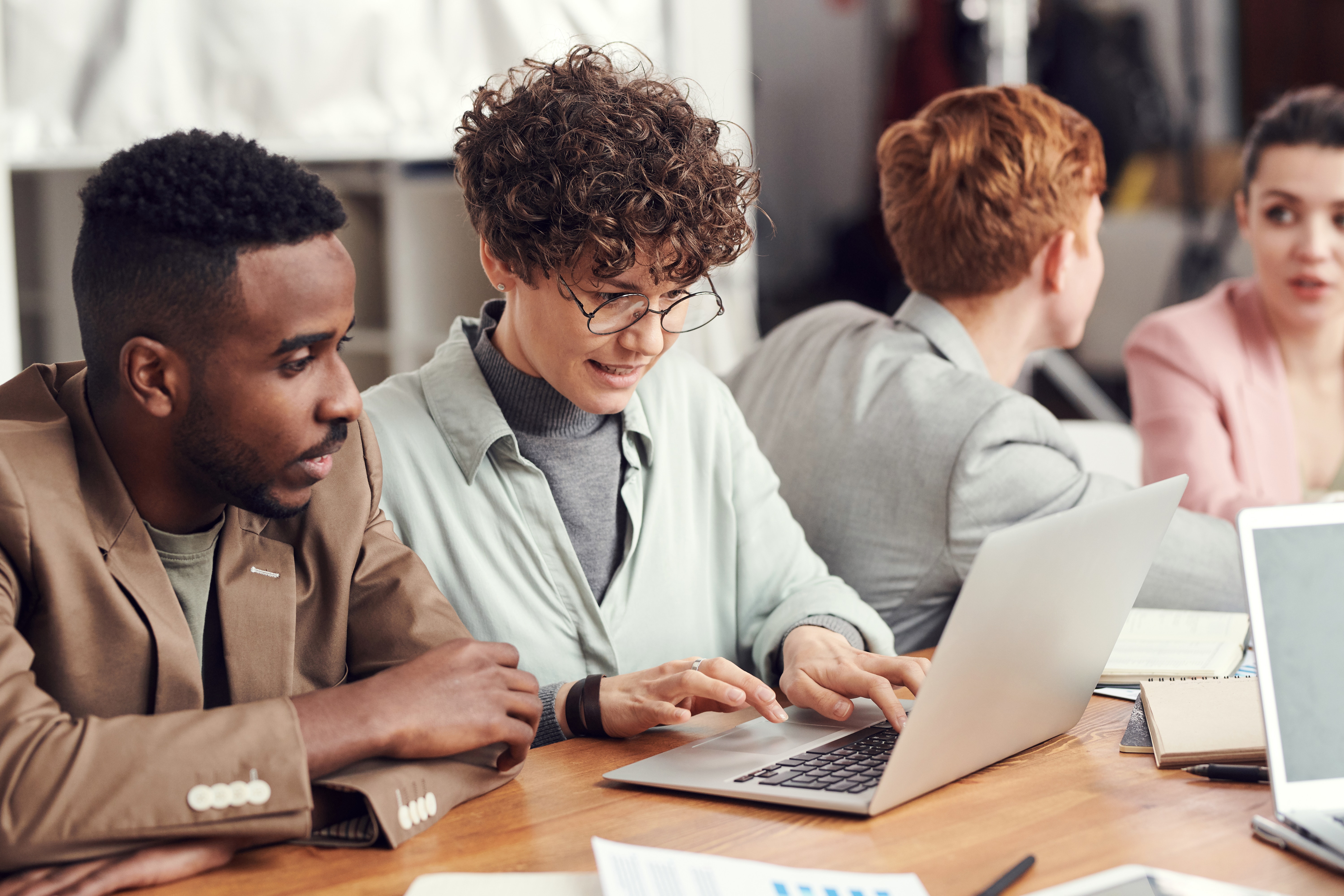 Two people sitting at a laptop while one is typing.