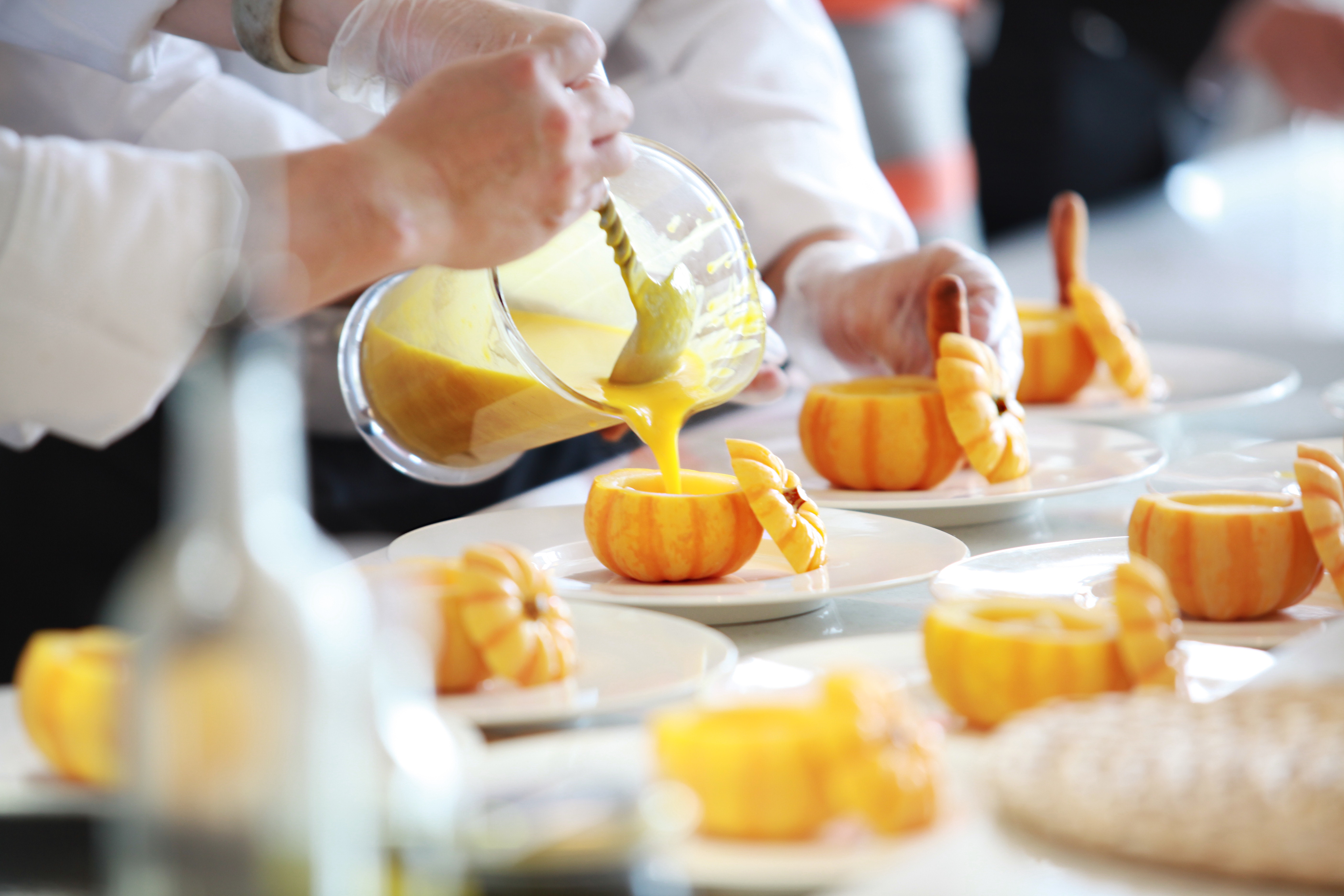 A person ladling puree into empty pumpkins.