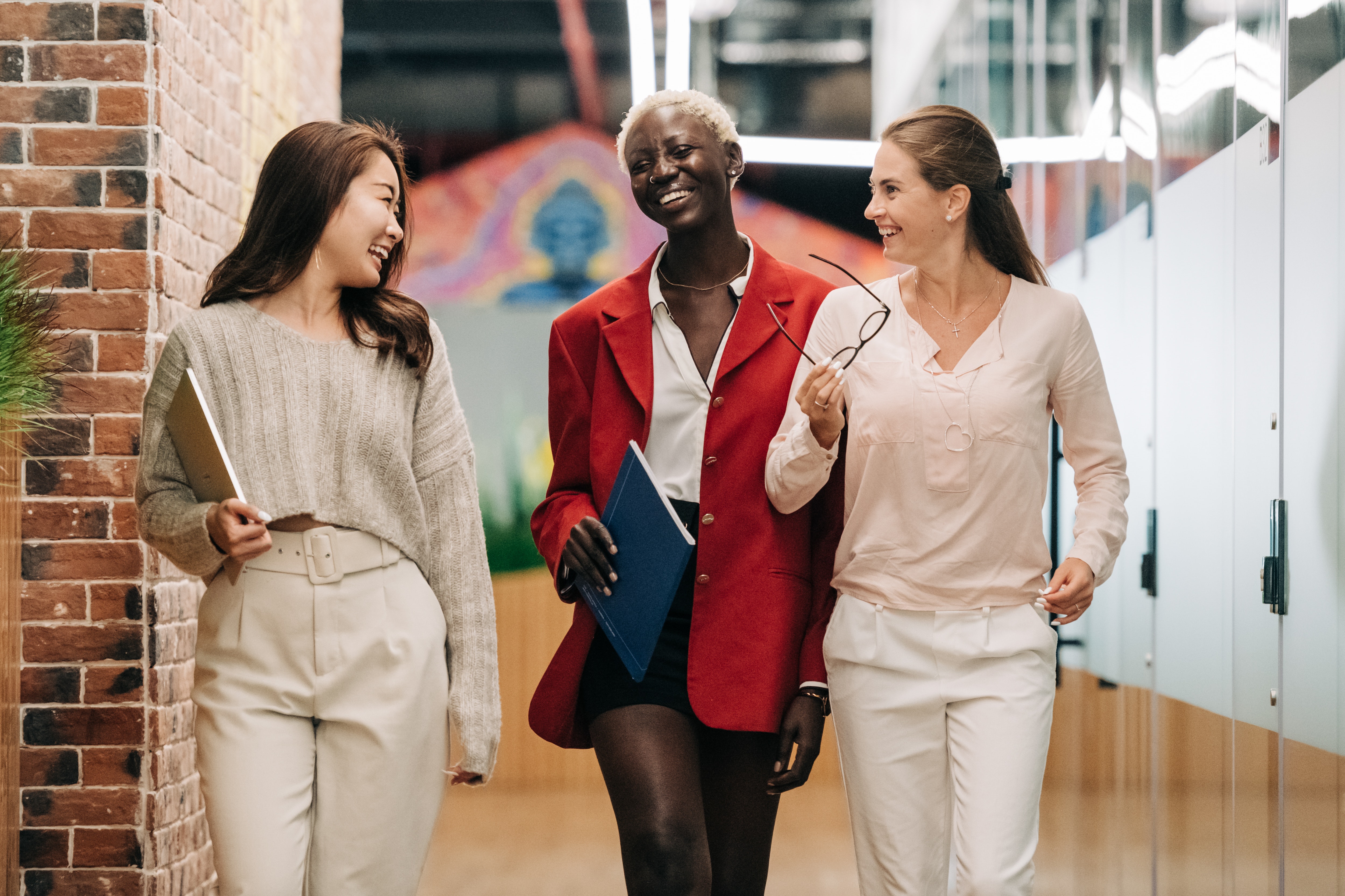 A photo of three ladies, who could be managers or a manager and staff, walking down a hallway laughing and talking.