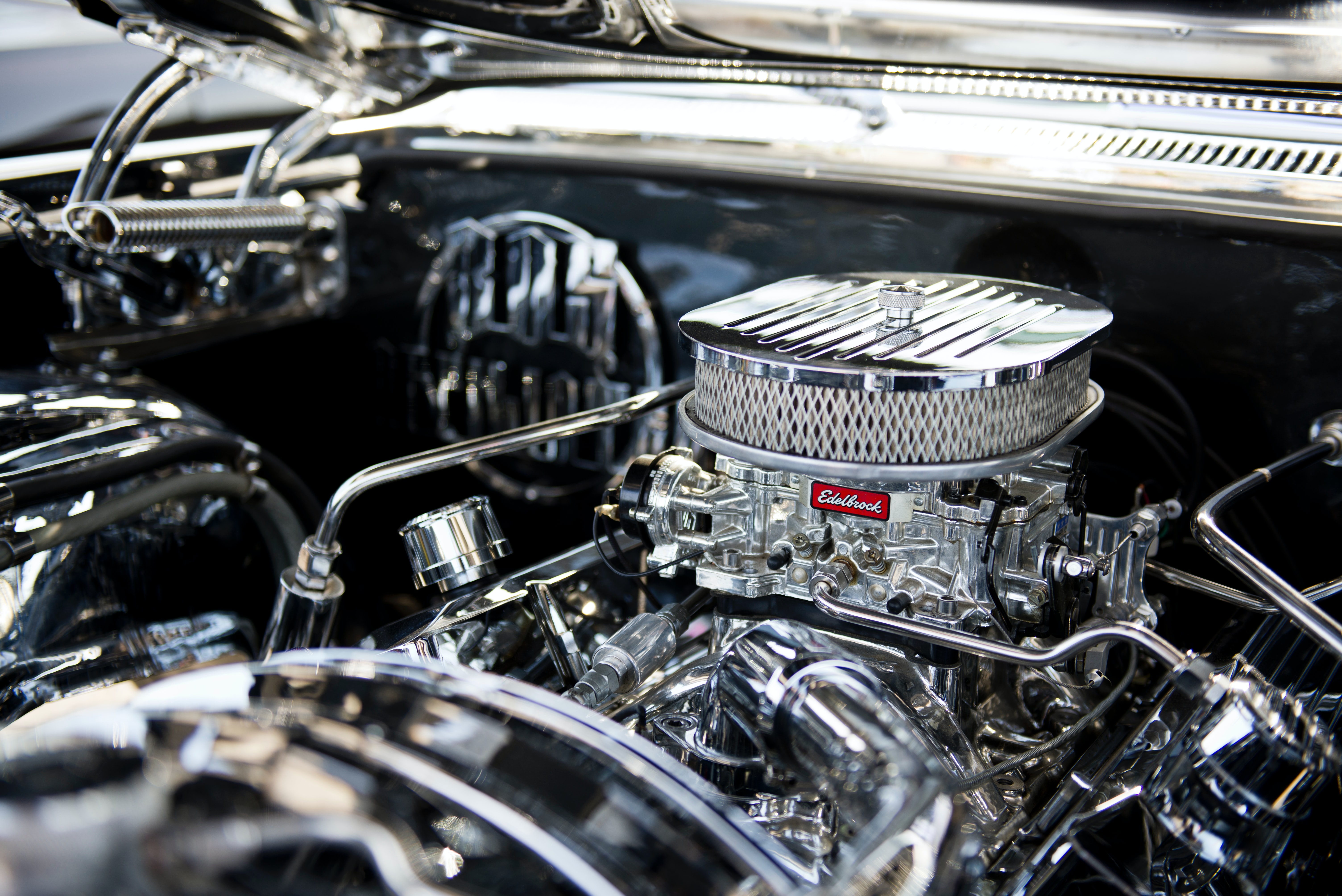 A photo of the top of probably a high performance car engine all in shinny chrome. The engine's shinny chrome air filter is the the dominant feature in the photo.